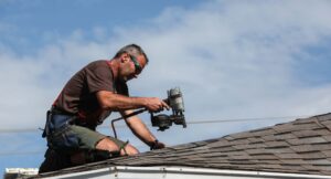 roofer on roof using a nail gun to install roof