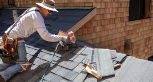 roofer on roof using a nail gun to install roof